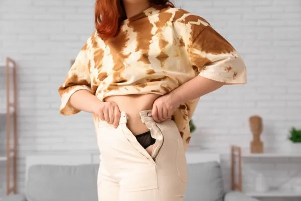 Image of woman trying to do her trousers up after pregnancy weight gain Doncaster