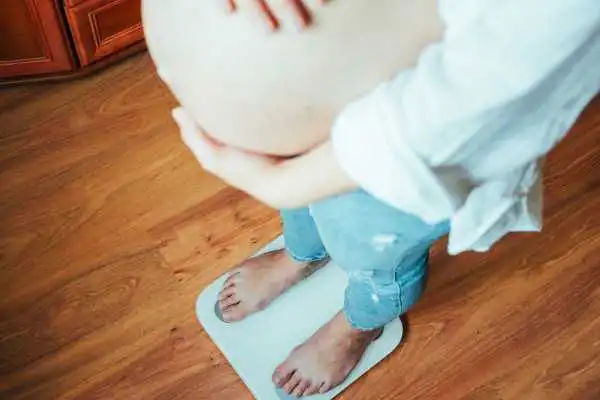 Image of woman weighing herself and experiencing weight gain through pregnancy Doncaster